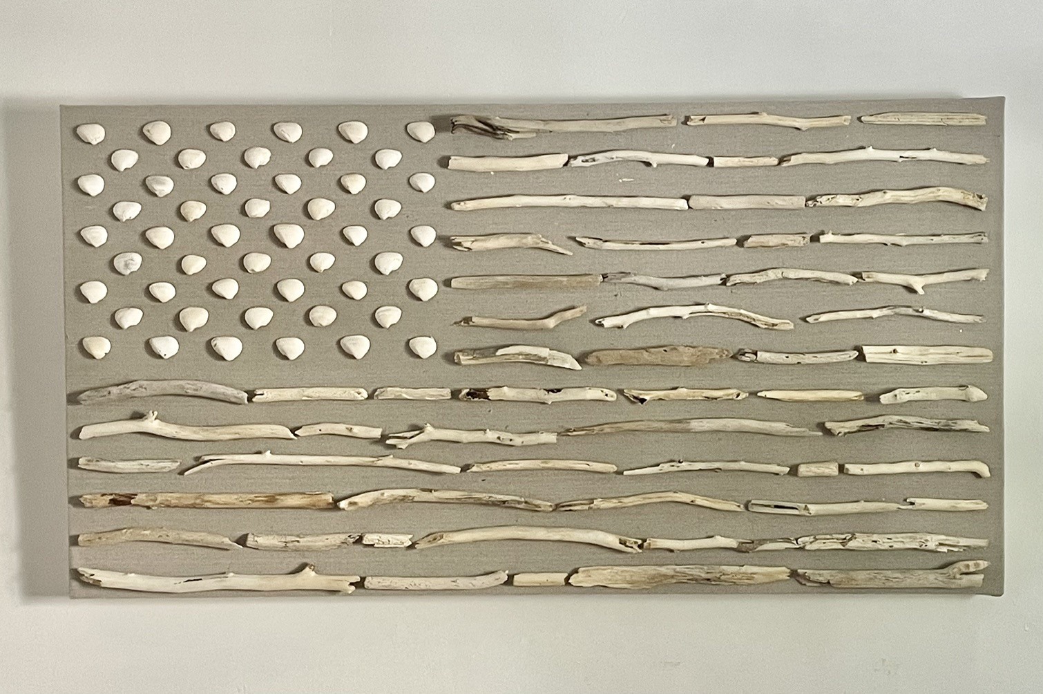 Muted flag assemblage made with white branches and pale stones on a gray field