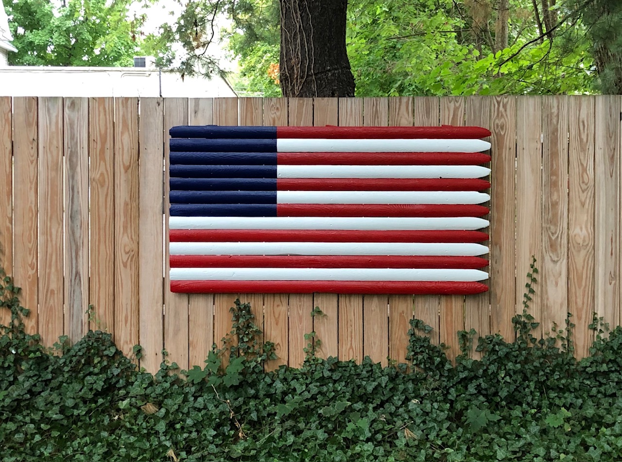 Red, white, and blue flag assemblage mounted on a wood fence