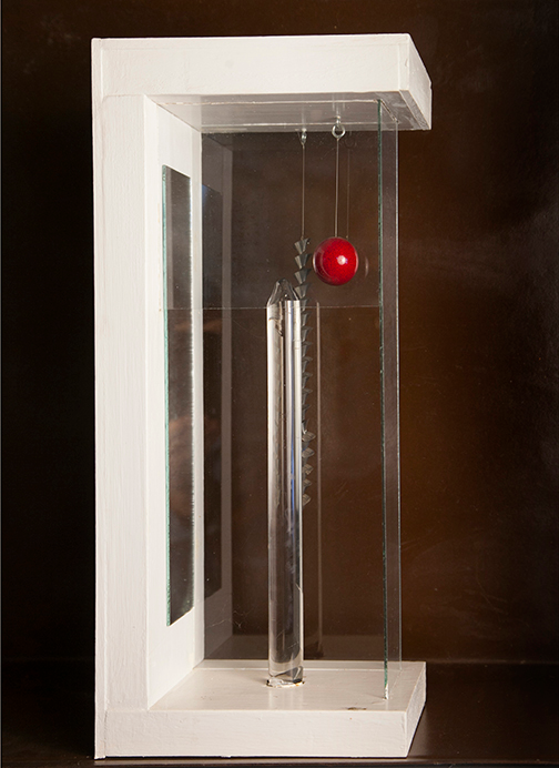 Assemblage piece with a red sphere suspended in a clear and white enclosure