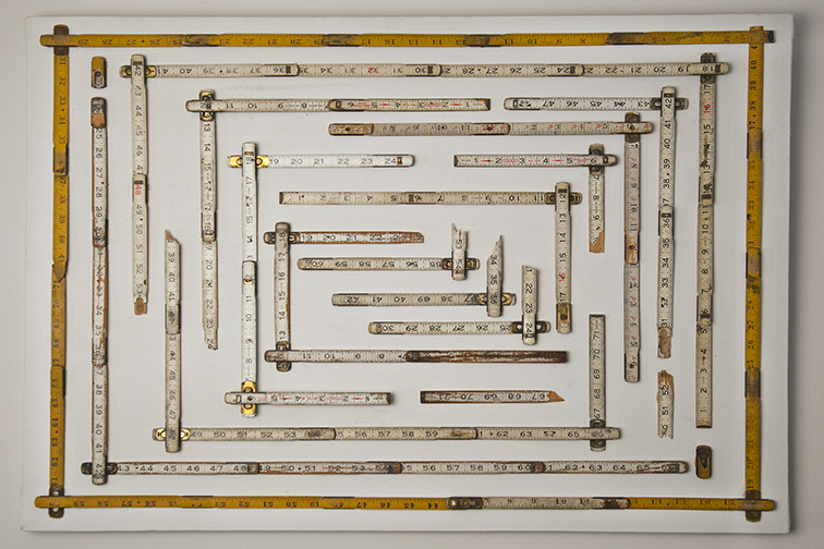Assemblage composed of many vintage measuring rules arranged on a white panel